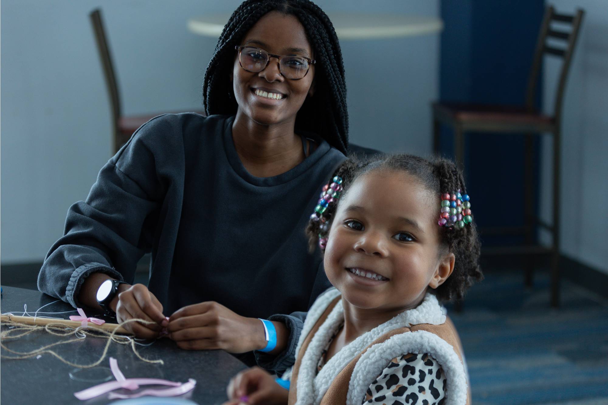 A student and a child sitting at a table and working on a craft